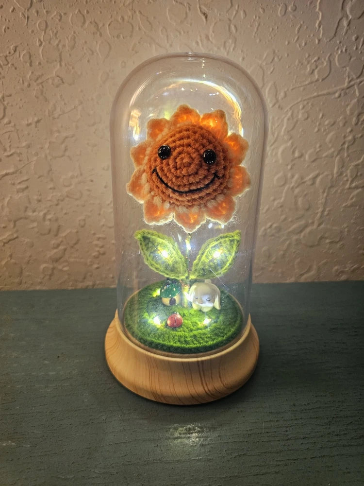Light-up crocheted sunflower with smiling face in clear dome, glowing green base