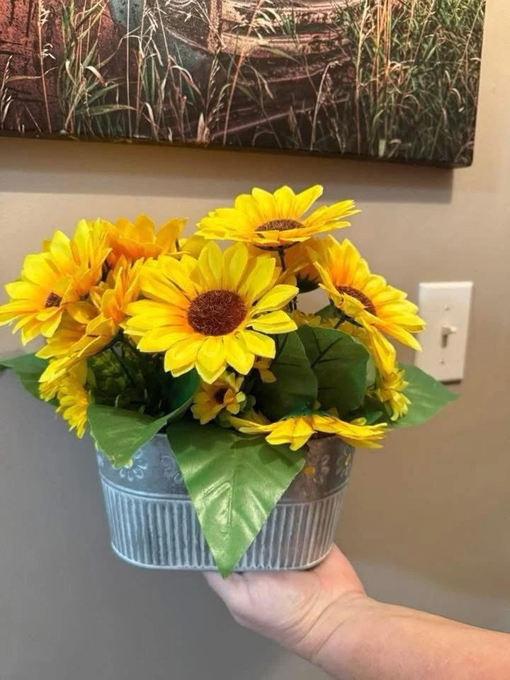 Artificial sunflower centerpiece in a ribbed metal pot with yellow blooms and green leaves