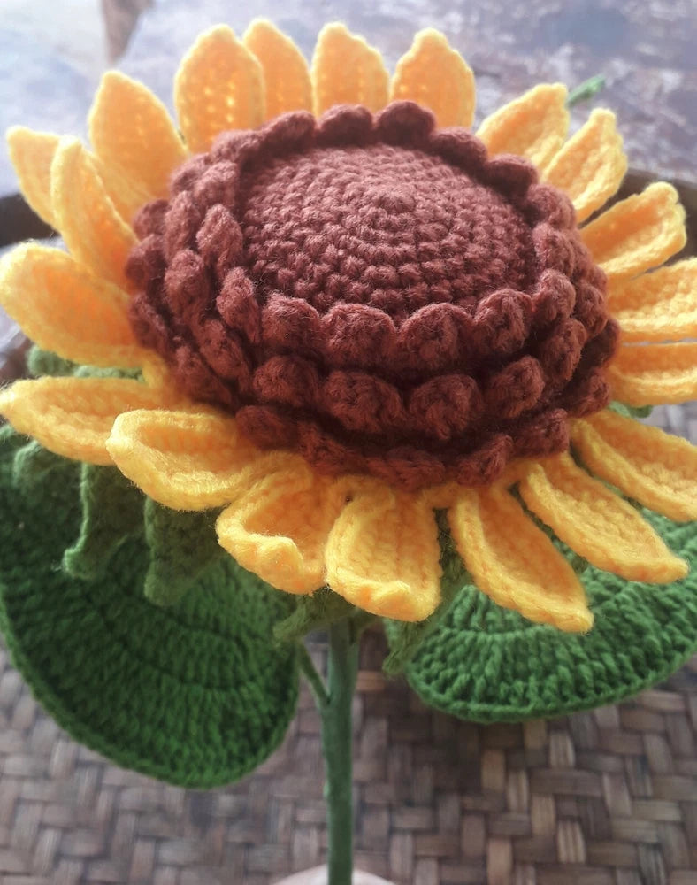 Handmade crochet sunflower with brown center, yellow petals, and green leaves