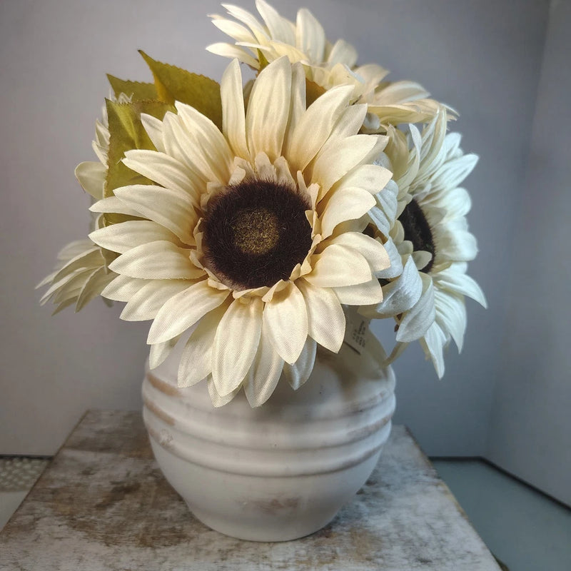 Artificial sunflower arrangement with cream petals and dark centers in white vase