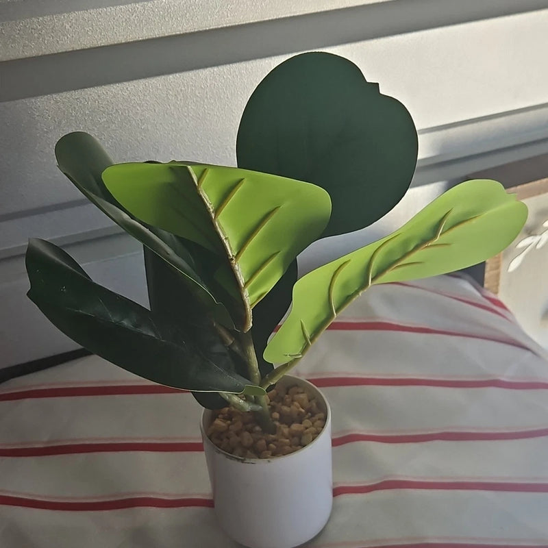 Artificial leaf and foliage houseplant with green leaves in a white round pot