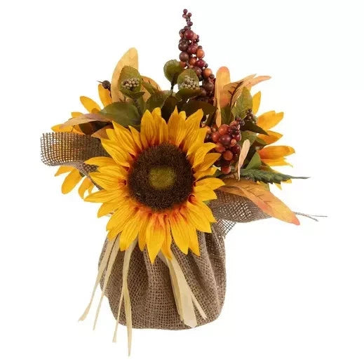 Faux sunflower and berry floral arrangement in burlap wrap with green leaves
