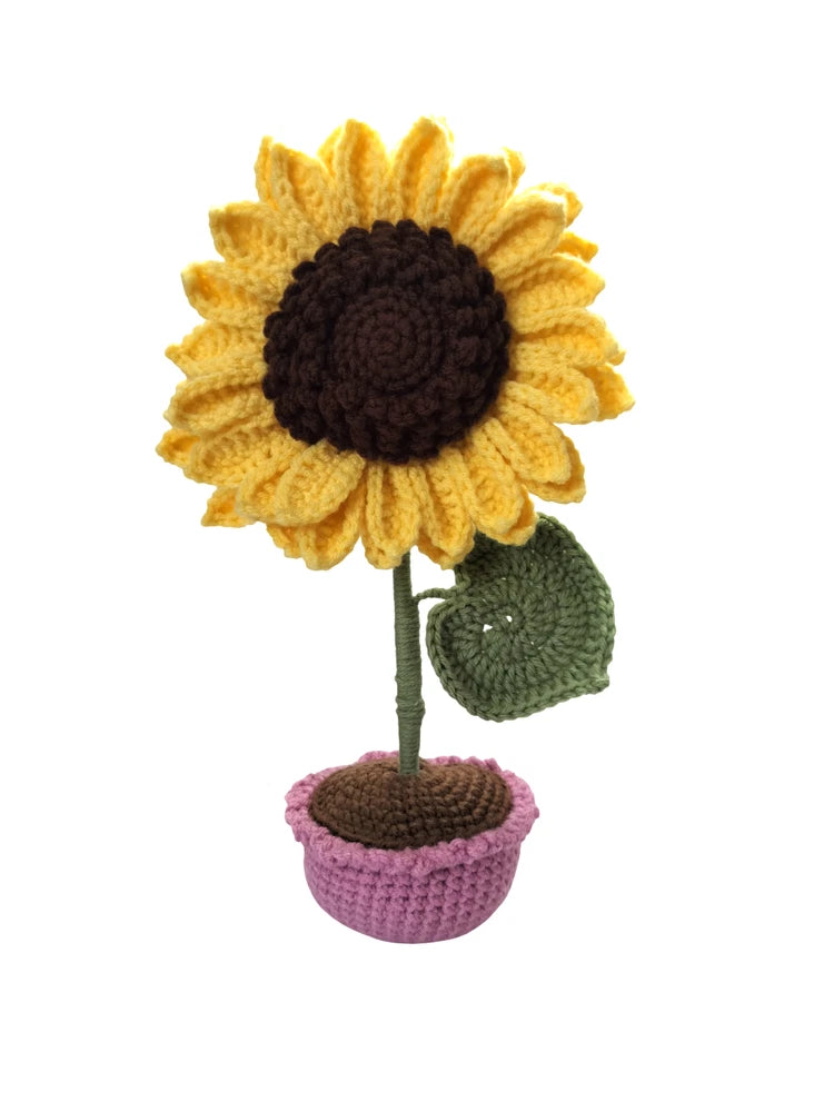 Handmade crochet sunflower with yellow petals and dark center in purple pot with green leaf