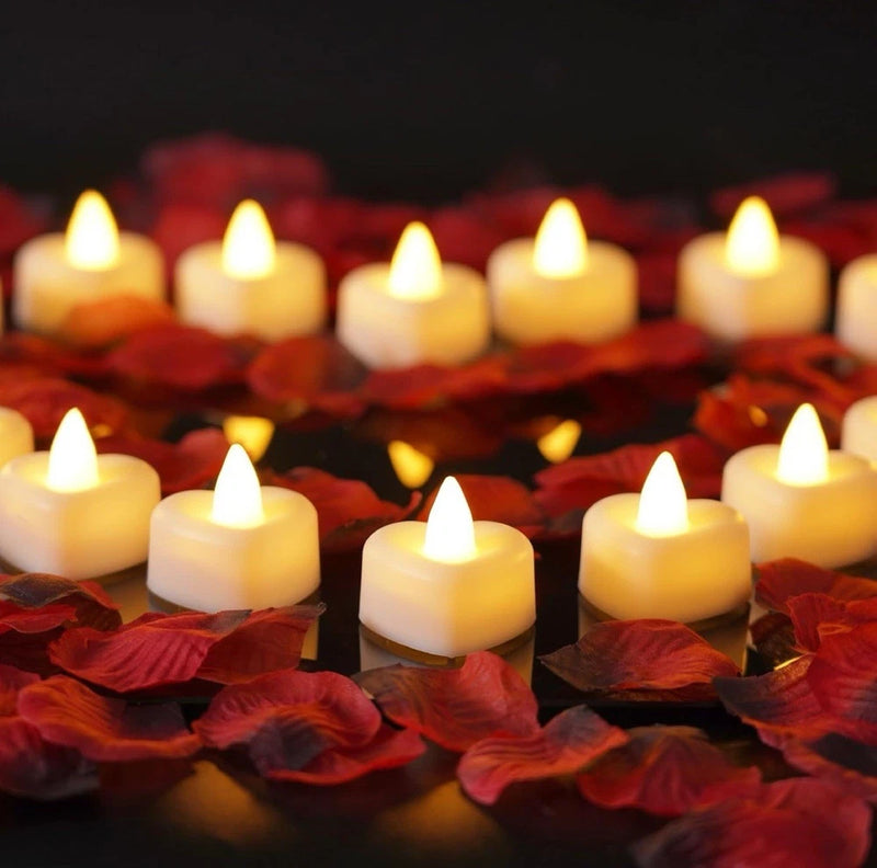 Artificial rose petal decor with lit LED tea lights, scattered on red petals