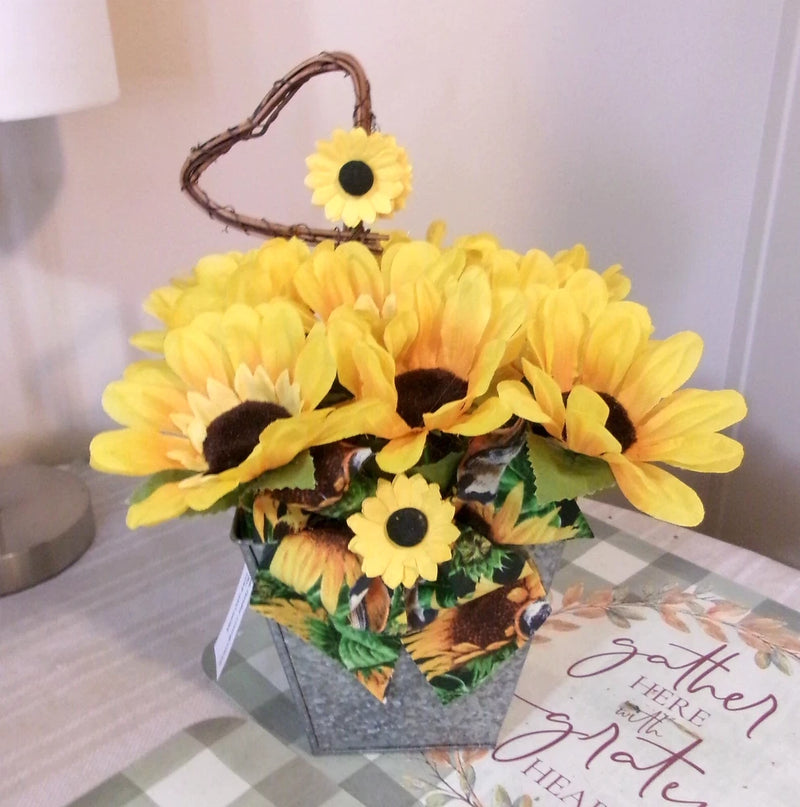 Heart-shaped sunflower centerpiece in fabric basket with yellow blooms