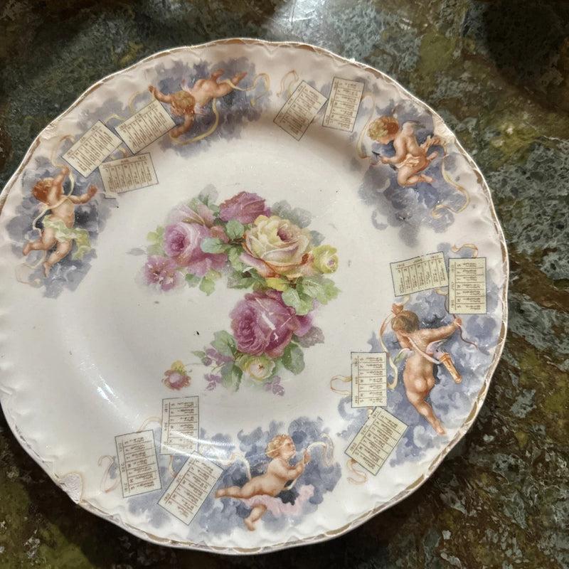 Vintage decorative plate with floral bouquet and cherub figures around rim
