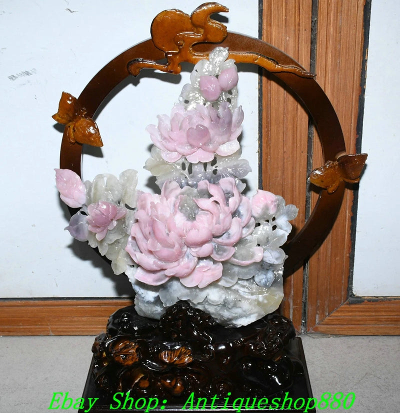 Pink and white carved peony jade statue with ornate circular frame and dark pedestal base