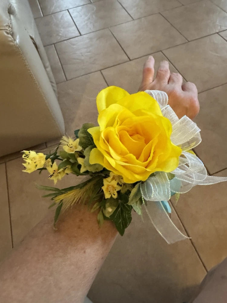 Yellow rose wrist corsage with white sheer bow and green filler leaves