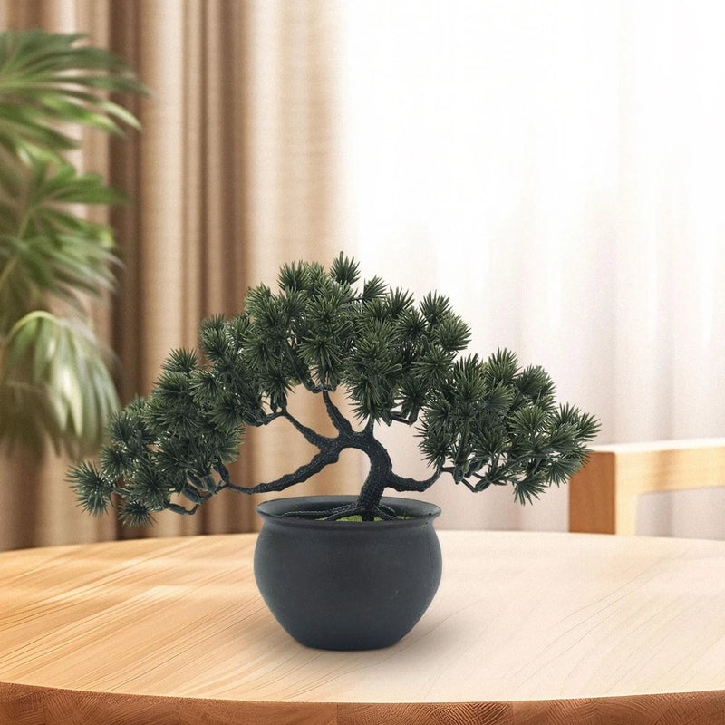 Artificial bonsai tree with dark green foliage in gray round pot on tabletop