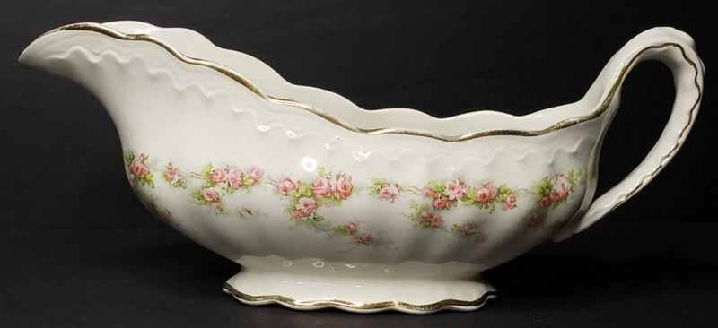 Porcelain gravy boat with floral pattern and gold trim, curved spout and handle