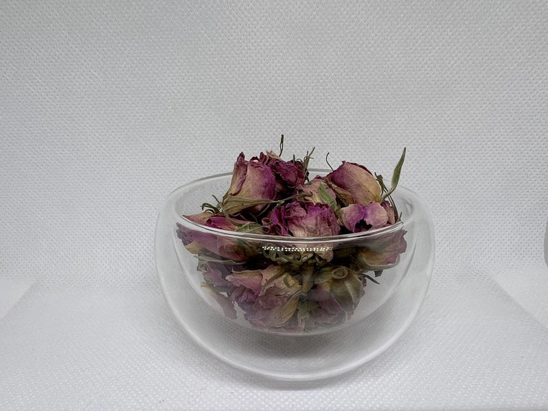 Dried rose buds in a clear glass bowl, pink and deep rose tones