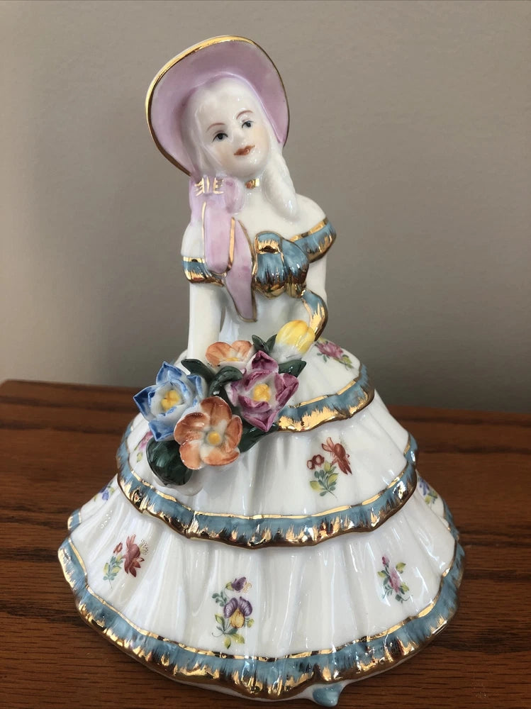 Porcelain figurine of a girl in a bonnet holding a bouquet of flowers