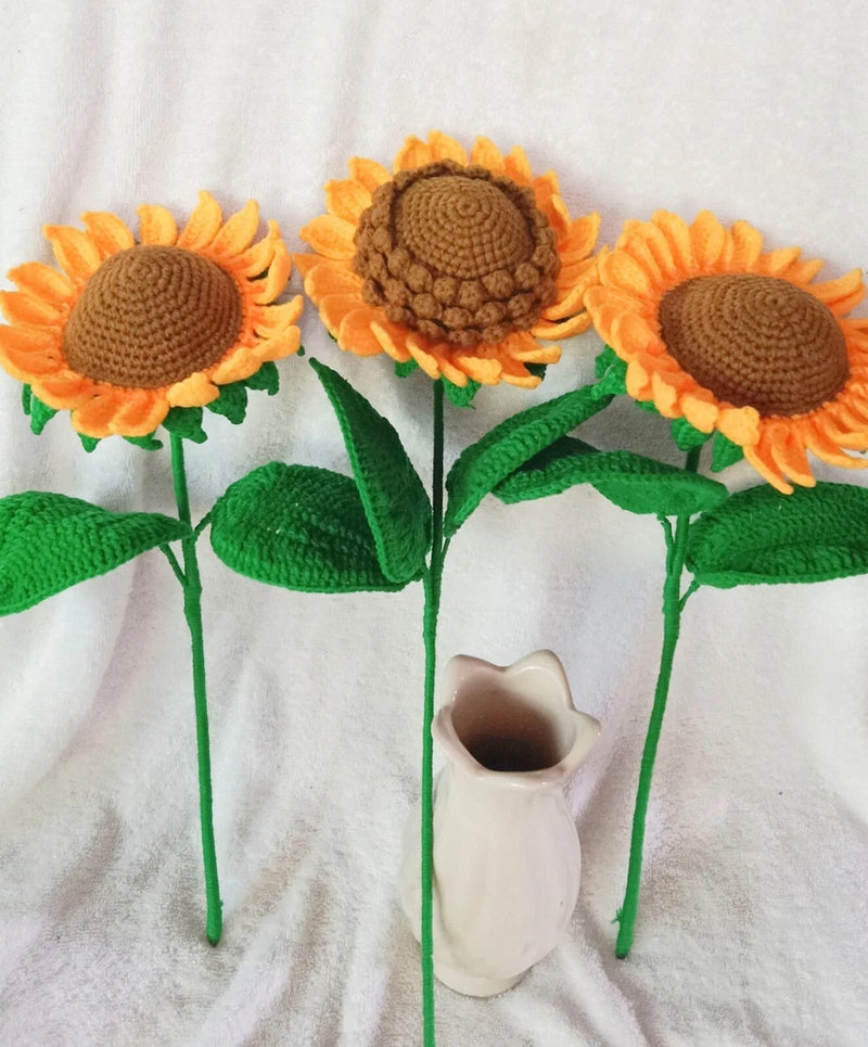 Three handmade crochet sunflower stems with orange petals, brown centers, and green leaves