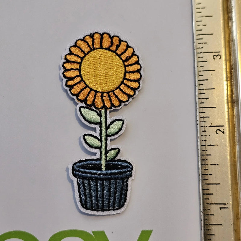 Embroidered sunflower patch with golden flower, green leaves, and dark striped pot