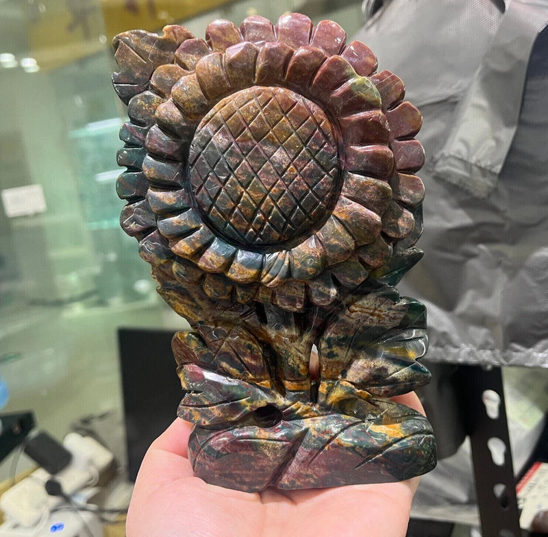 Carved ocean jasper flower skull figurine with sunflower motif, polished stone.