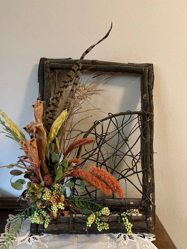 Dried faux flower arrangement in rustic garden gate with mixed dried blooms and grasses