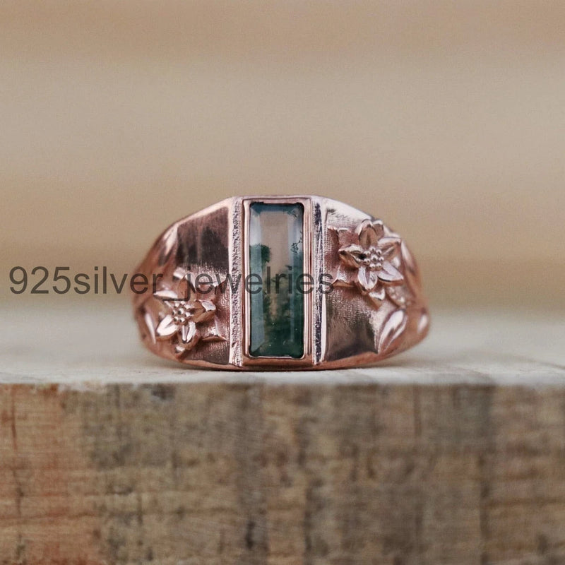Solid silver ring with green rectangle moss agate and flower-like side details.