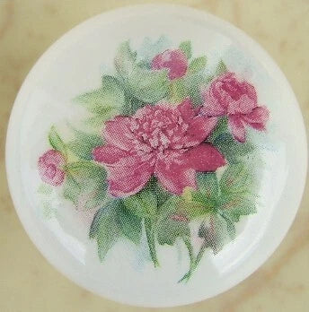 Round cabinet knob with pink peonies floral design on pale background.