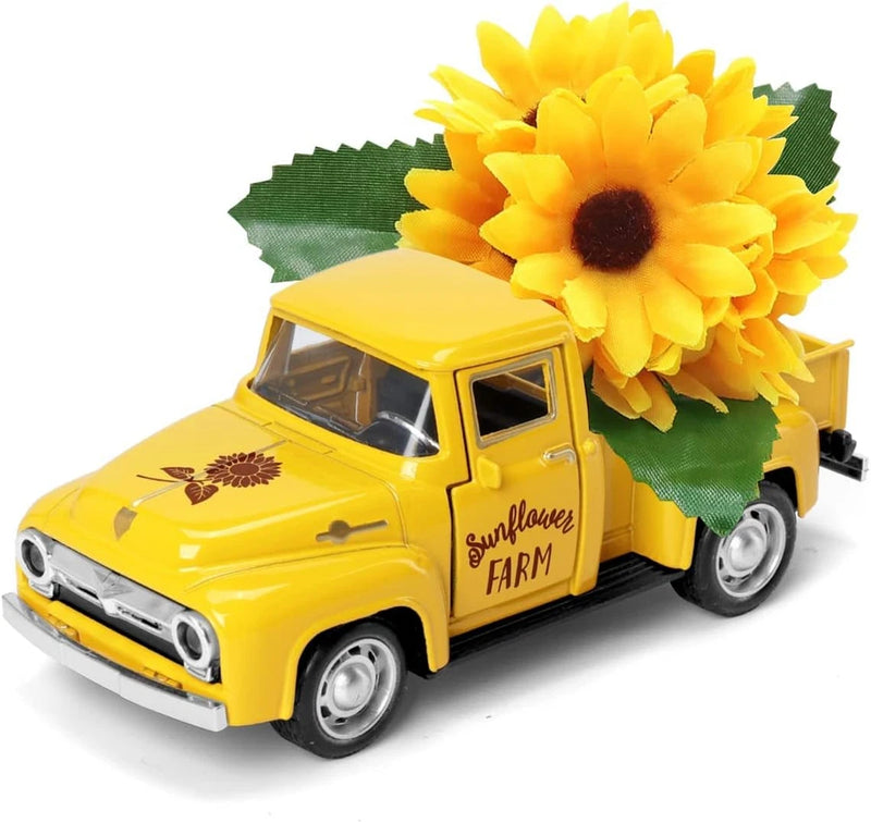 Yellow metal farm pickup truck with large artificial sunflower on green topper