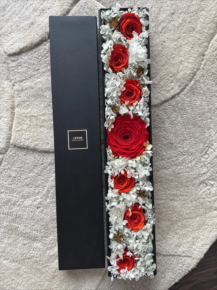 Preserved red rose bouquet in dark gift box with white filler flowers
