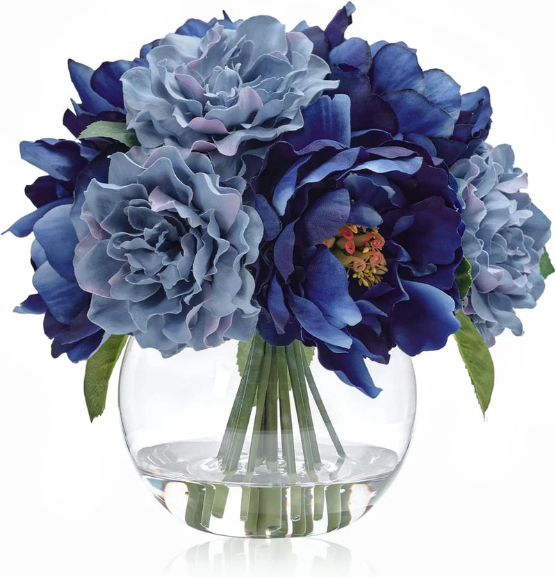 Blue faux peony silk bouquet with green leaves in clear glass vase