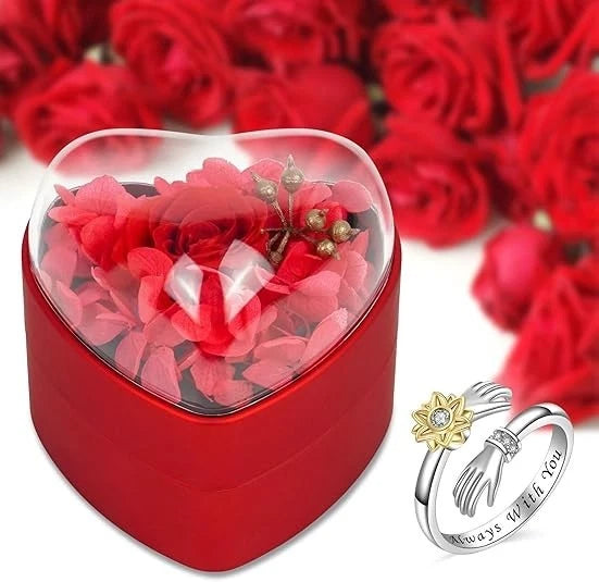 Heart-shaped red gift box with clear lid, pink rose arrangement and two rings