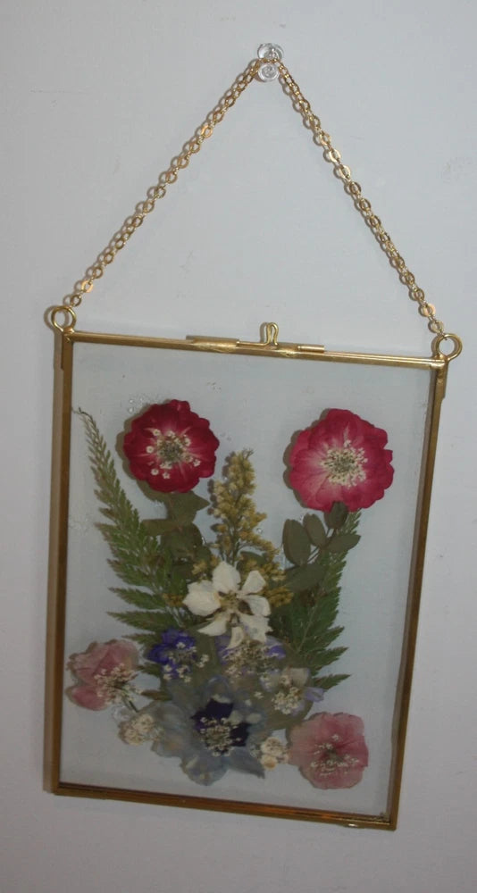 Gold chain wall hanging with rectangular frame of pressed poppy flowers and greenery