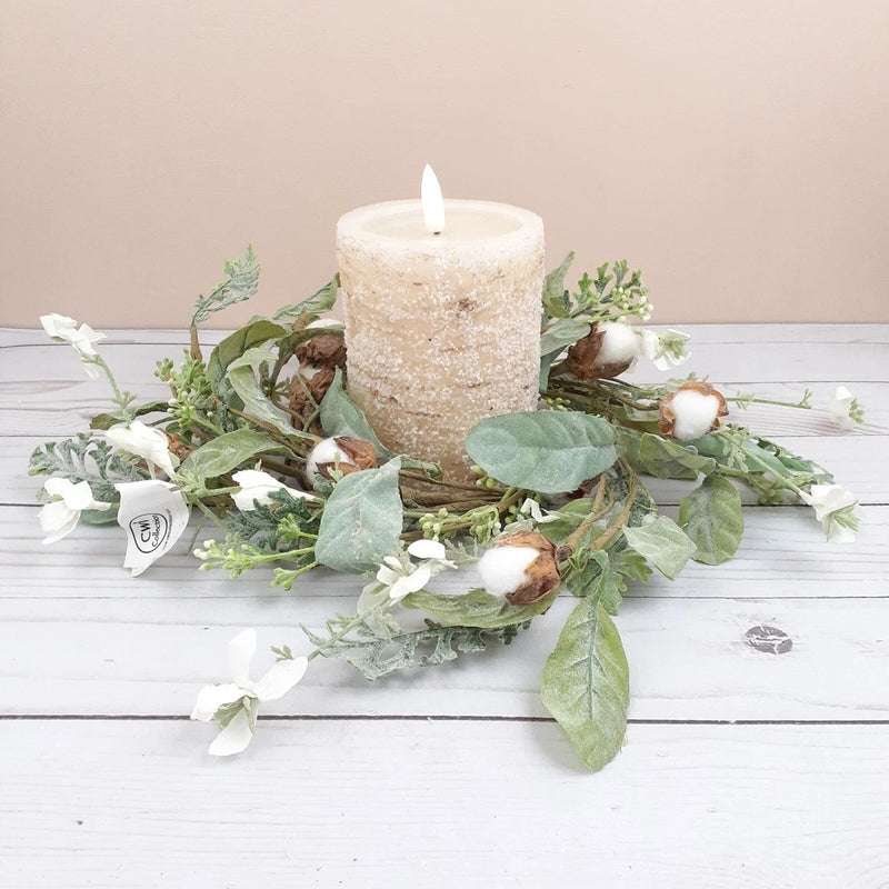 Floral cotton candle ring with green leaves and white dried flowers around pillar candle