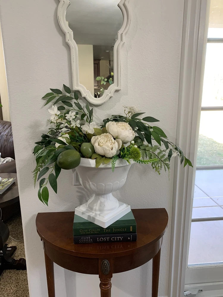 Artificial flower arrangement in white urn with white peonies, green leaves, and lime accents