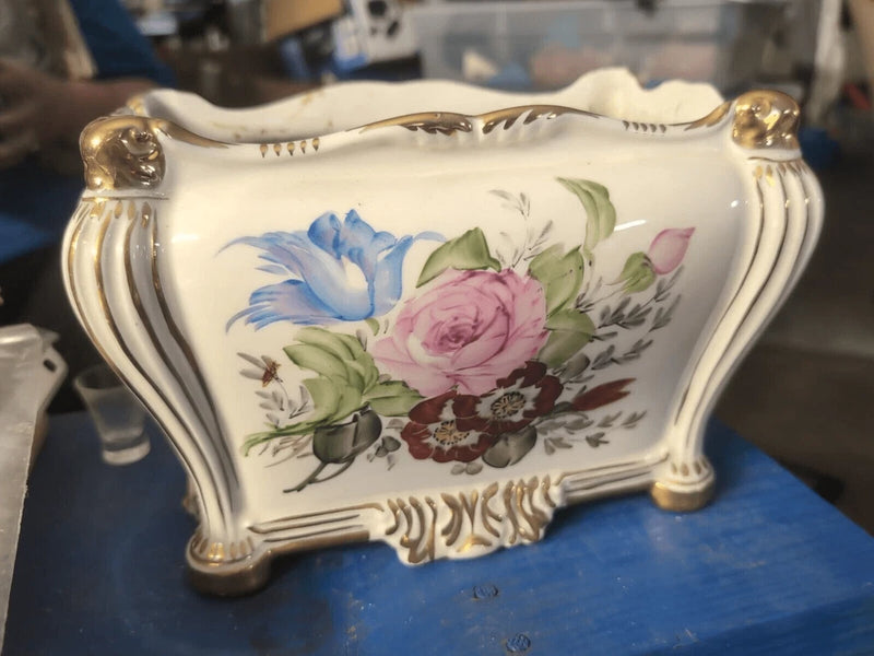 White ceramic cachepot with hand-painted blue, pink, and green floral pattern, handles