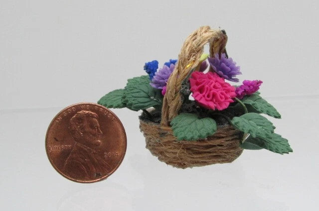 Miniature carnation flower arrangement in small wicker basket with pink and purple blooms